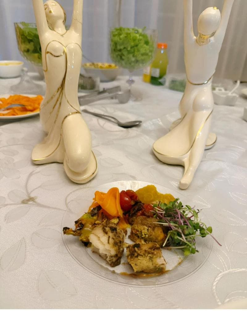 Prato de degustação com frango, abóbora e microverdes entre esculturas decorativas